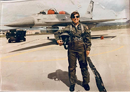 Dr. Hardy stands in front of an airplane in flight gear, when she was in the US Air Force.